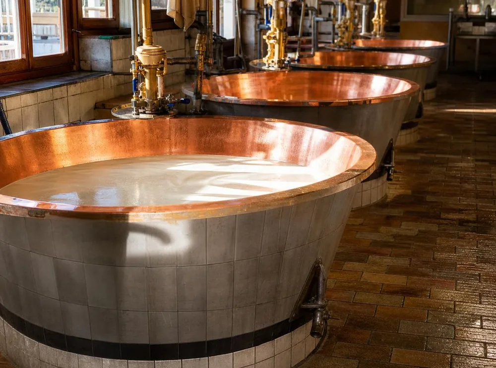 Cuves en cuivre de lait dans une fromagerie de Parmigiano Reggiano tôt le matin